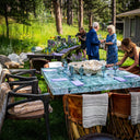Natural fluorite dining table set for an elegant outdoor dinner, showcasing vivid blue-green mineral movement, crystalline detail, and a polished stone surface.