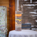 Decorative cylindrical lamp with a textured design on a surface, wooden wall background