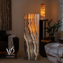 Illuminated Tangerine Onyx rectangular floor lamp glowing with cream, amber, orange, and charcoal vertical banding