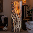 Sculptural Tangerine Onyx tower illuminated to reveal translucent amber stone and dramatic vertical veining