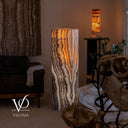 Handcrafted Tangerine Onyx floor lamp glowing in a luxury interior with vertically layered natural stone patterns