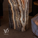 Sculptural Tangerine Onyx tower illuminated to reveal translucent amber stone and dramatic vertical veining