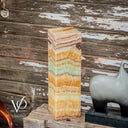 Decorative stone column with layered pattern against a rustic wooden background, featuring the Vilona logo.