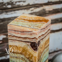 Onyx cube with multicolored stripes on a rustic wooden background Vilona Onyx