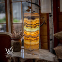 Decorative lamp with layered pattern on a surface near a window with blurred outdoor view