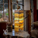 Decorative lamp with multicolored layers on a wooden surface, blurred window in the background