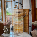 Decorative stone column with natural patterns on a table, surrounded by indoor plants and decor.