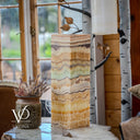 Decorative vase with layered pattern on a surface near a window with natural light.