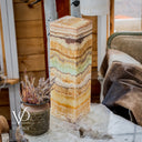 Decorative stone column with layered patterns on a table, next to a small plant in a pot.