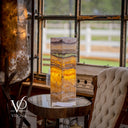 Decorative lamp with multicolored pattern on a round table in a room with large windows.