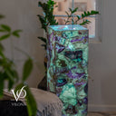 A rectangular Vilona decorative lamp made of polished purple and green marbled stone, glowing with a soft blue light from within, styled in a home interior setting.