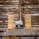 Decorative sculpture between two colorful stone pillars against a rustic wooden wall.