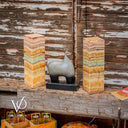 Decorative elephant sculpture between two colorful stone pillars against a rustic wooden wall.