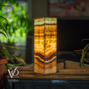 Decorative lamp with layered design on a wooden surface, blurred background