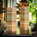 Two decorative lamps with layered design on a reflective surface, blurred indoor background