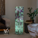 Angled view of the illuminated Fluorite floor lamp showing two polished sides and a square stone top.