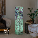 Wide room view of the illuminated Fluorite tower beside natural stone furniture and a window.