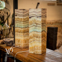 Two onyx table lamps with a layered pattern on a wooden surface, blurred background.