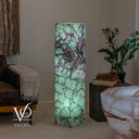 Green and purple Fluorite lamp glowing beside a leather sofa and a potted plant.