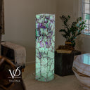 Wide room view of the illuminated Fluorite tower beside natural stone furniture and a window.