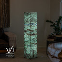 Angled view of a glowing green Fluorite tower showing mineral bands across two polished stone faces.