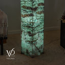 Lower detail of the illuminated Fluorite lamp showing pale green crystal textures and dark wavy bands.
