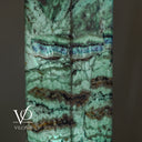 Close-up of blue-violet, cream, and charcoal bands crossing luminous green Fluorite on the tower’s polished corner.