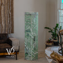 Unlit Fluorite floor lamp with pale green stone, white veining, and blue-violet accents beside a leather sofa.