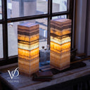 Stacked square lamps with multicolored layers on a surface near a window, featuring the brand 'Vilona'.