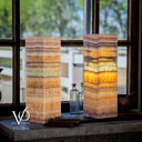 Two layered stone lamps on a windowsill with blurred outdoor view