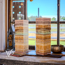 Decorative onyx columns on a windowsill with a scenic view outside.