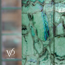 Close-up of turquoise and violet banding within translucent mint-green Fluorite beside the lamp’s polished corner.