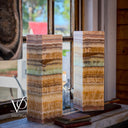 Two stacked stone blocks with layered patterns on a wooden surface, blurred outdoor background.