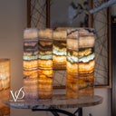 Decorative cylindrical lamps with multicolored layers on a wooden table, branded 'Vilona'.