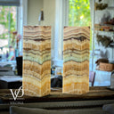 Two onyx stone lamps on a wooden surface with a blurred indoor background