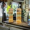 Two onyx columns on a wooden surface with a blurred indoor setting