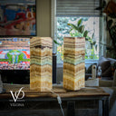 Two stacked stone lamps on a wooden table with a blurred living room background