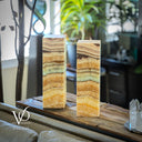 Two onyx columns on a wooden surface with a blurred indoor background