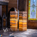 Decorative stone columns with a stained glass window in the background