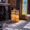 Decorative stone pedestal with a stained glass window in the background
