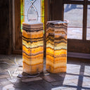 Two onyx column lamps with a stained glass window in the background