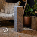 Decorative stone pedestal in a home setting with plants and furniture.