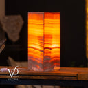 Decorative lamp with wavy orange and red pattern on a wooden surface, blurred background