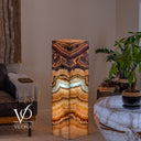 Full-length view of the illuminated Aqua Onyx floor lamp with angular rose veining and a luminous aqua center band.