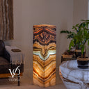 Illuminated corner view of the Aqua Onyx tower with golden waves and dark veining across two stone faces.