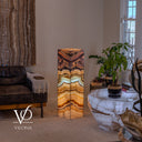 Illuminated 43.5-inch Aqua Onyx tower floor lamp beside a lounge chair and natural stone table.