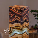 Close-up of the glowing Aqua Onyx tower with intricate rose and charcoal layers above a crystalline aqua band.