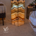Lower section of the illuminated Aqua Onyx tower showing pale aqua, honey-gold, and cream bands around its corner.