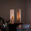 Illuminated White Ice onyx table lamp pair with pearl-white stone, amber mineral formations, and smoky vertical banding.