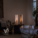 Wide interior view of two glowing White Ice onyx table lamps beside an onyx coffee table and indoor plants.